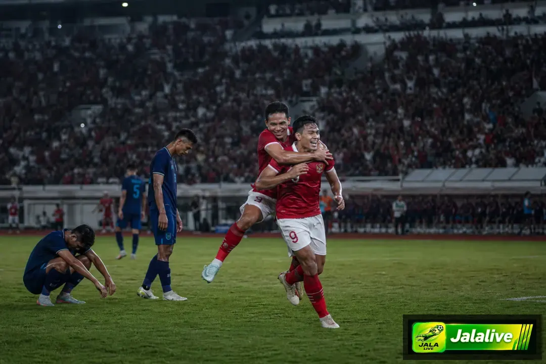 Suasana pertandingan sepak bola Indonesia dengan pemain merayakan gol di stadion
