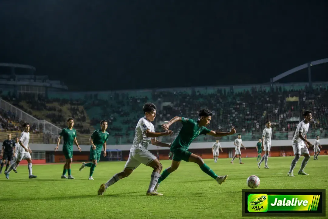 Pemain sepak bola bertanding di stadion Indonesia di bawah lampu malam